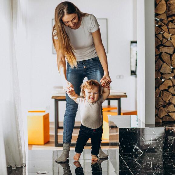 Frau geht mit ihrem Kind gemeinsam barfuß durch das Haus